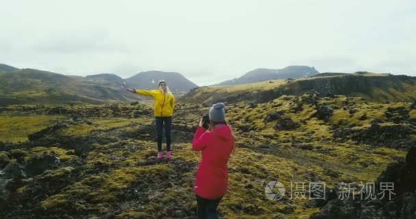 直升机拍摄的游客有拍摄在山区。两名妇女在冰岛的熔岩场拍照