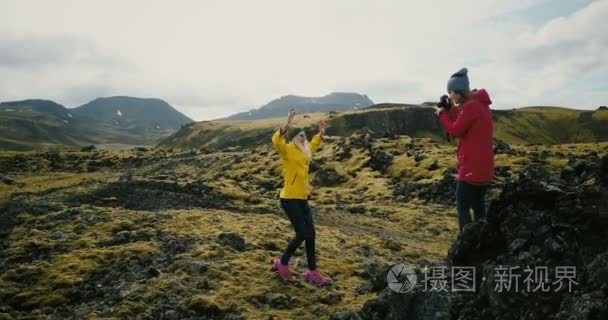 摄影师在山上拍摄的旅游妇女的照片。在冰岛熔岩场拍摄的女孩