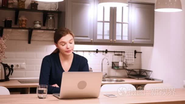 头疼, 疲倦的疲乏的妇女工作在手提电脑在厨房