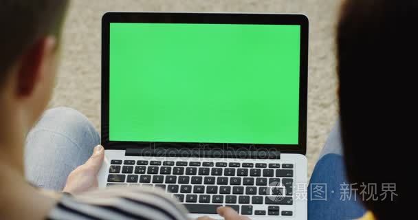 查看肩上的女人和男子坐在他们面前的笔记本电脑和男子打字键盘上。绿色屏幕。色度键