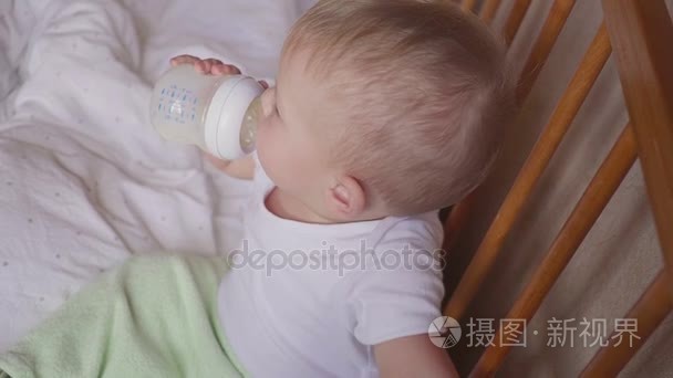 微笑的男婴站立和喝牛奶从瓶视频