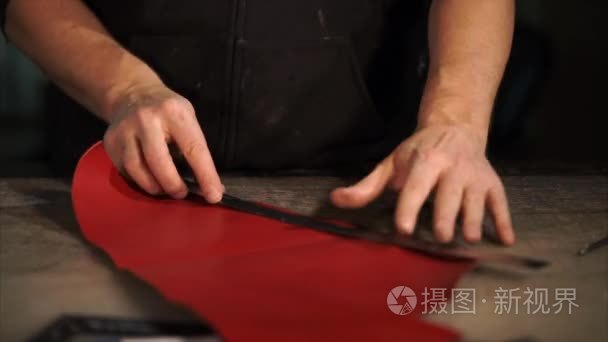近距离拍摄的一个人的手  削减了皮革材料的工作