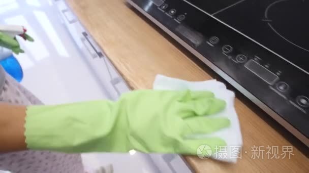 妇女用绿色手套清洁她的厨房