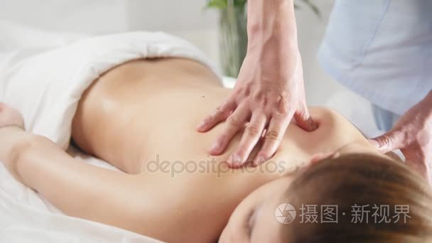 为年轻女子的背部按摩。男子 rmassaging 为年轻的金发女