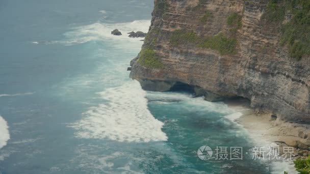 海浪冲破石崖。印度尼西亚巴厘岛热带海滩鸟瞰图。慢动作