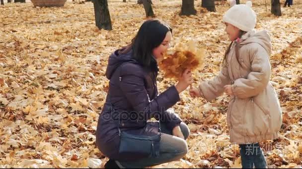 小女孩在公园里给妈妈一束秋叶