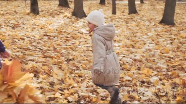 愉快的小女孩在秋天公园与她的母亲一起演奏