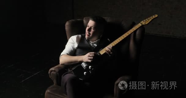 吉他手坐在扶手椅和演奏独奏视频