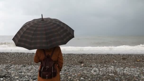 暴风雨海附近有雨伞的女人视频