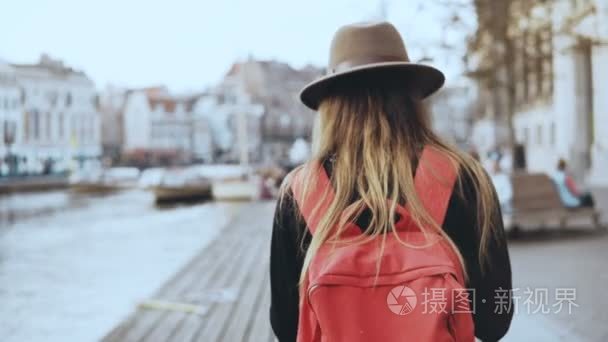 女游客散步, 在河码头拍照。长头发的女孩, 红色背包送图片给朋友在线。4k