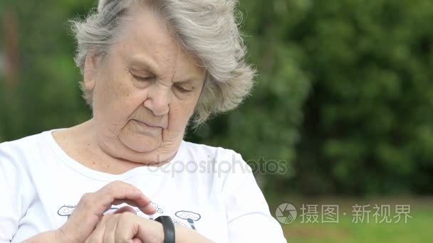 老妇人看一个腕带健身追踪器视频