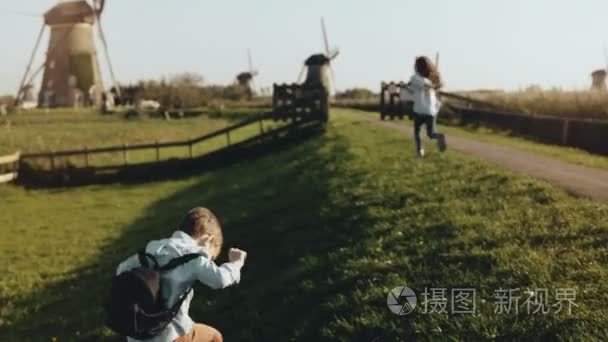 两个小孩在老风车农场附近玩耍。快乐的孩子们围着乡间乡村风光奔跑。快乐和快乐。4k