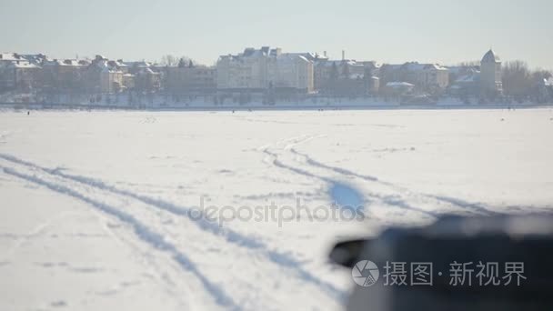 雪地摩托在冰冻的湖面上。一个雪橇的仪表盘的看法以乌克兰的旗子在冬天城市的背景