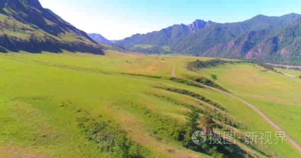 在晴朗的夏日清晨  空中的乡村山路和草地。沥青公路与河道