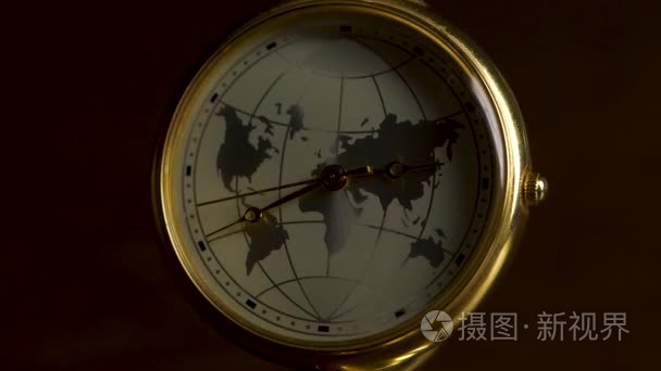 时钟与一张行星地球的图片在一张木桌上隔绝在黑背景。一个时区和飞机的复古时钟的细节。黑暗的房间里有模糊光线的地球时钟。地球小时概念