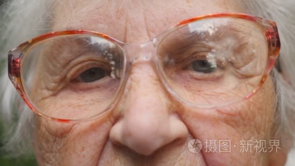 戴眼镜的老妇人在看镜头。关闭祖母的画像。慢动作