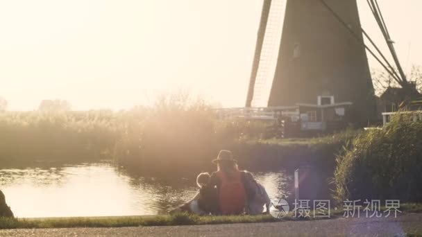 日落时分, 母亲带着两个孩子靠近小湖。和平的看法高加索家庭一起在一个码头。4k 后视图视频