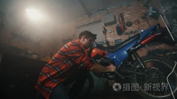一个人在黑暗的车库里修摩托车视频