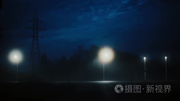 一个令人惊叹的漆黑的夜晚公路交通的看法。惊人的神秘电影拍摄。城市灯光下的风景移动雾