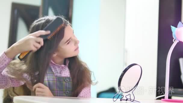 小女孩梳头发做发型。少女吹起她的头发梳和镜子室内