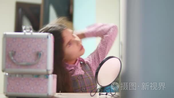 小女孩梳头发做发型。少女吹起她的头发梳和室内镜室内