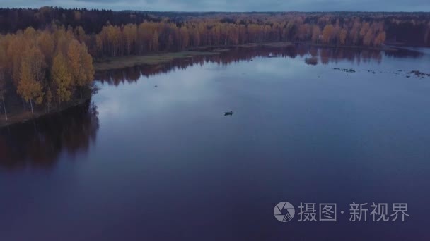 小机动船漂浮在碧波荡漾的湖水中  在秋天的森林里。空中射击