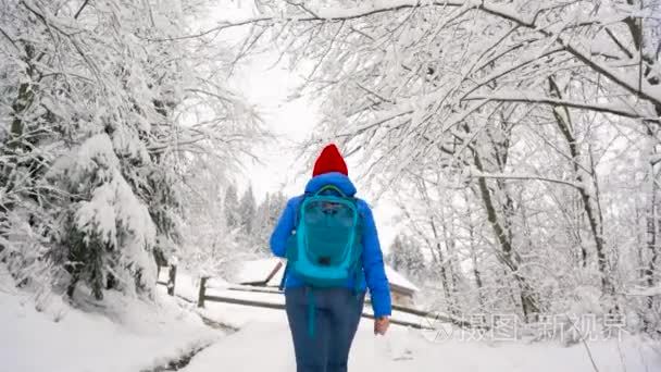 女人爬上白雪覆盖的山  转过身  微笑着向某人挥手致意。晴朗的严寒天气