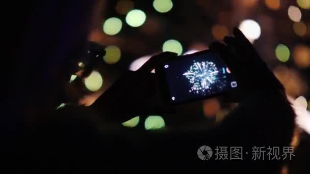 一个女人欣赏夜空中的烟火。用你的智能手机拍照。4k 10 位视频