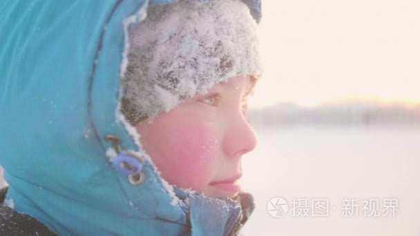 一个少年在冬季公园  脸部特写。日落的时间。在清新的空气中漫步。健康的生活方式