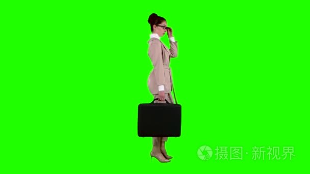 女商人在他的手的情况下调情矫正眼镜。绿色屏幕。侧面视图