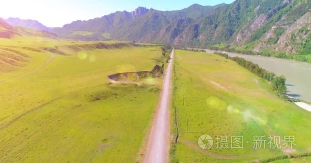 在晴朗的夏日清晨  空中的乡村山路和草地。沥青公路与河道