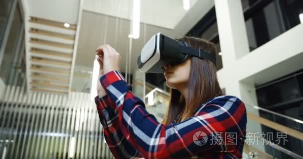 关闭的年轻女子长发和穿着在杂色衬衫滚动  录音和变焦  同时有一个 Vr 耳机在空气中。大白色大厅的背景。肖像拍摄。内