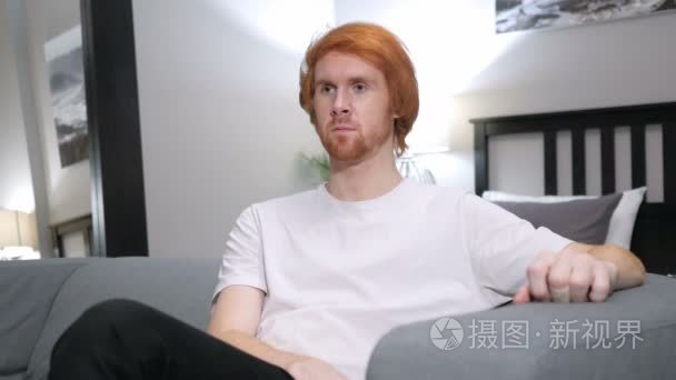 红头发的男人坐在沙发上的卧室视频