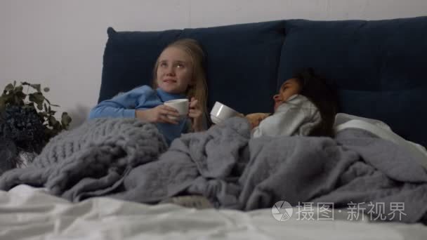 可爱的小女孩在床上喝茶和聊天视频