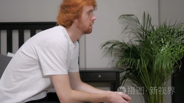 伤心的红头发的男人坐在床边视频