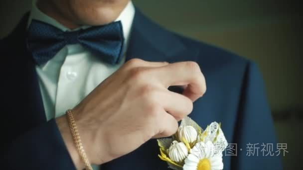 新郎调整婚礼胸花。剪辑.新郎胸花对一个人纠正他的口袋里的手