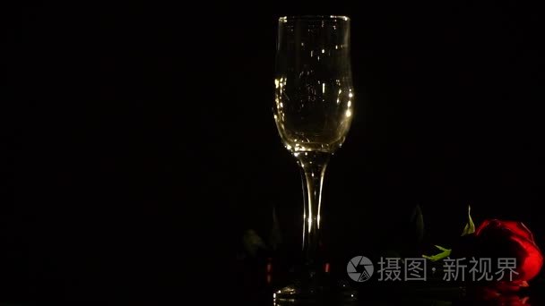 水晶香槟眼镜和黑色背景的红玫瑰