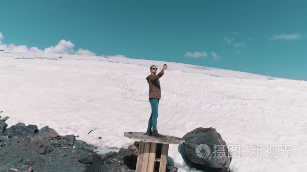 空中拍摄人采取自拍站在石头上的电缆线轴上雪山