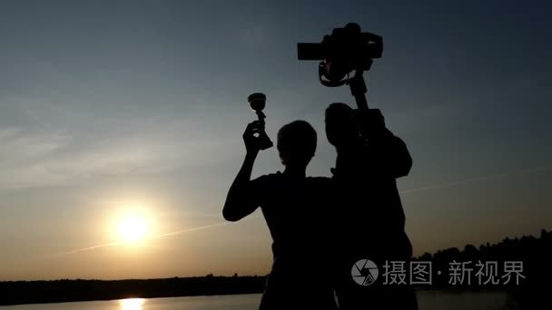 两个年轻人在日落时守着 stedicam 和冠军杯