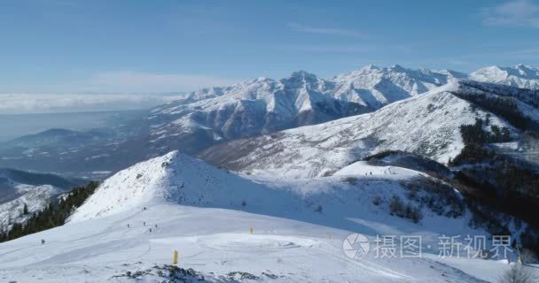 在阳光明媚的日子里  与人们一起在冬季雪山和滑雪场上向前空中俯视。阿尔卑斯山雪季节制订者 4 k 无人机飞行建立射击