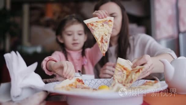 在比萨店的家庭聚餐。母亲和女儿在餐馆吃比萨饼