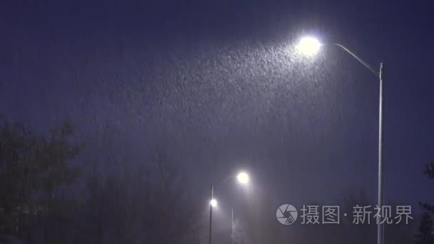 晚上雪落在灯柱的背景上。夜冬路灯随雪飘落