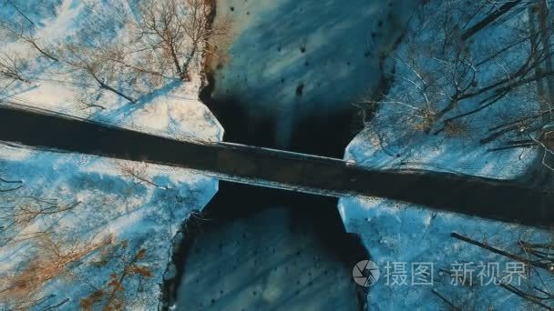 冬季森林镜头横跨冰冻湖大桥鸟瞰图视频