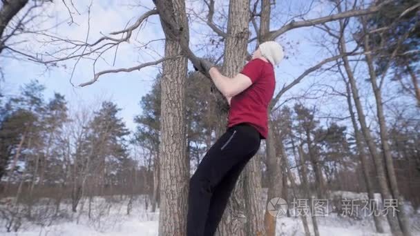 强壮的运动的年轻人在冬季公园的一支裸树上拉起  抬起腿