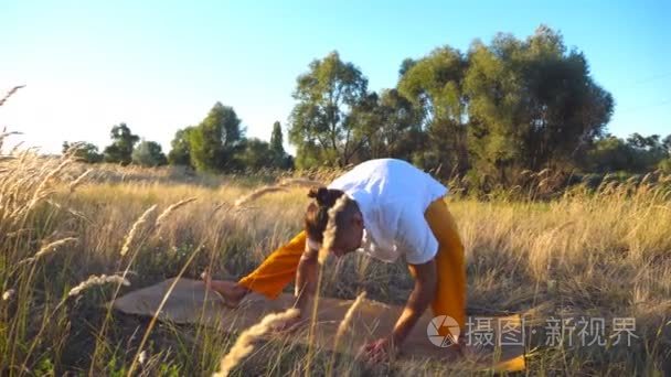 关闭运动的家伙练习瑜伽动作和立场在垫子上的领域。在阳光明媚的日子, 年轻人在草地上做运动。夏季景观背景。健康积极生活方式的概念