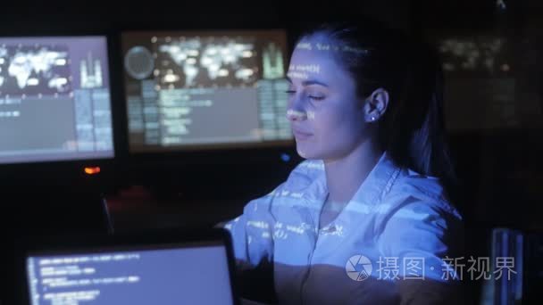 女黑客程序员是在电脑上工作的网络安全中心  充满了显示屏幕。她脸上的二进制代码