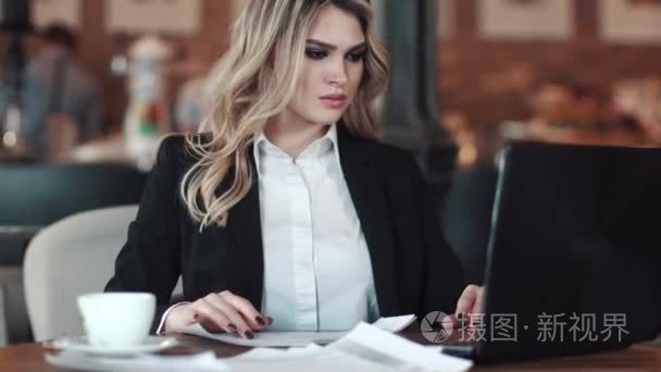 一个穿着商务服的年轻女士, 坐在咖啡桌上的笔记本上工作。在非正式场合工作的商务妇女