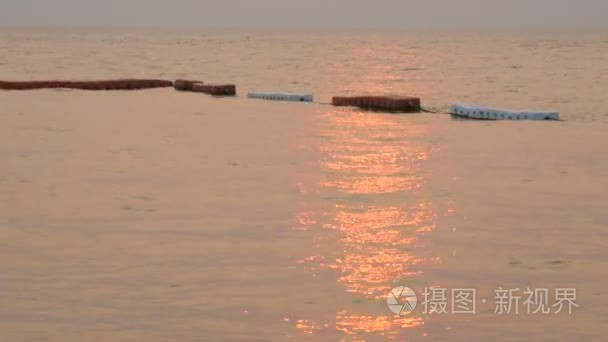 美丽的红色夕阳在海面上红白的浮标。海面上红太阳的光芒