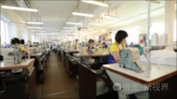 工业规模纺织厂, 工人在生产线上, 缝纫生产, 妇女工作为缝纫机, 缝纫车间, 模糊, 无法辨认