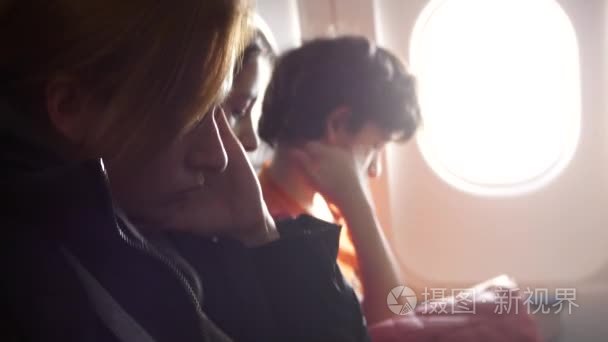 在飞机上的妇女与儿童在舷窗背景。4k. 飞机进入湍流区。女孩开始惊慌视频